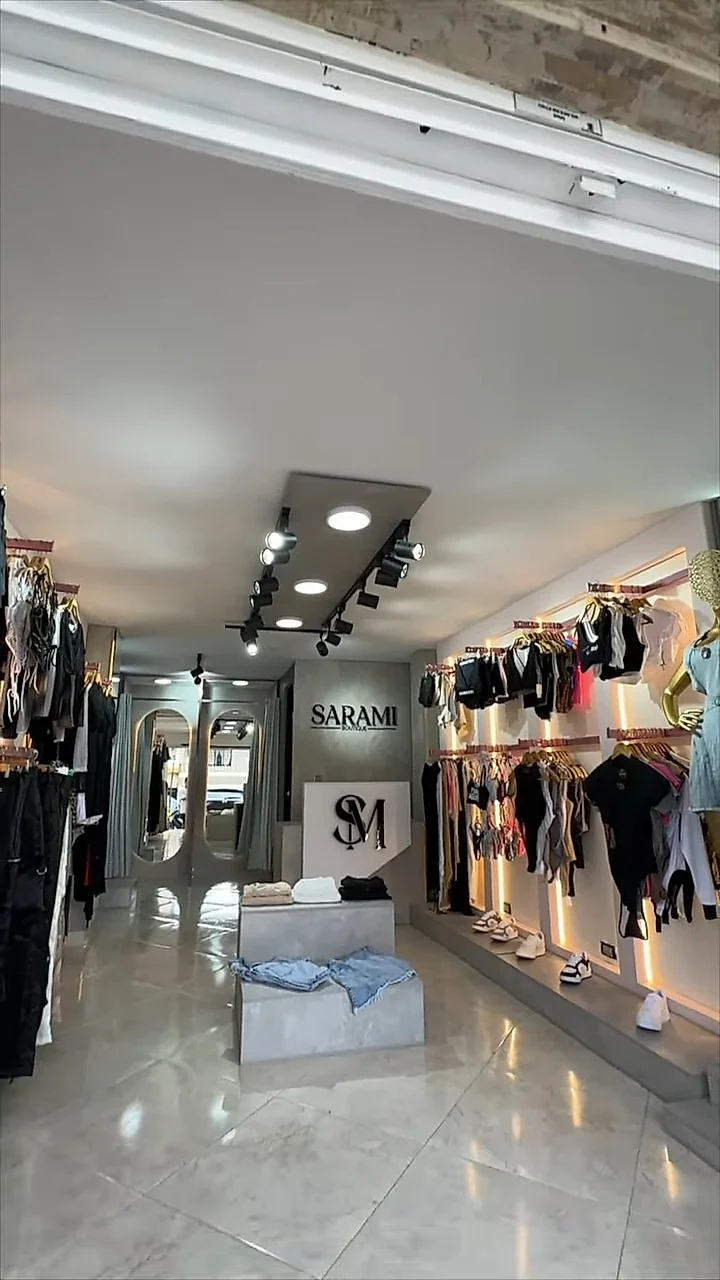 Pasillo de la tienda con percheros iluminados y el logo de SARAMI al fondo